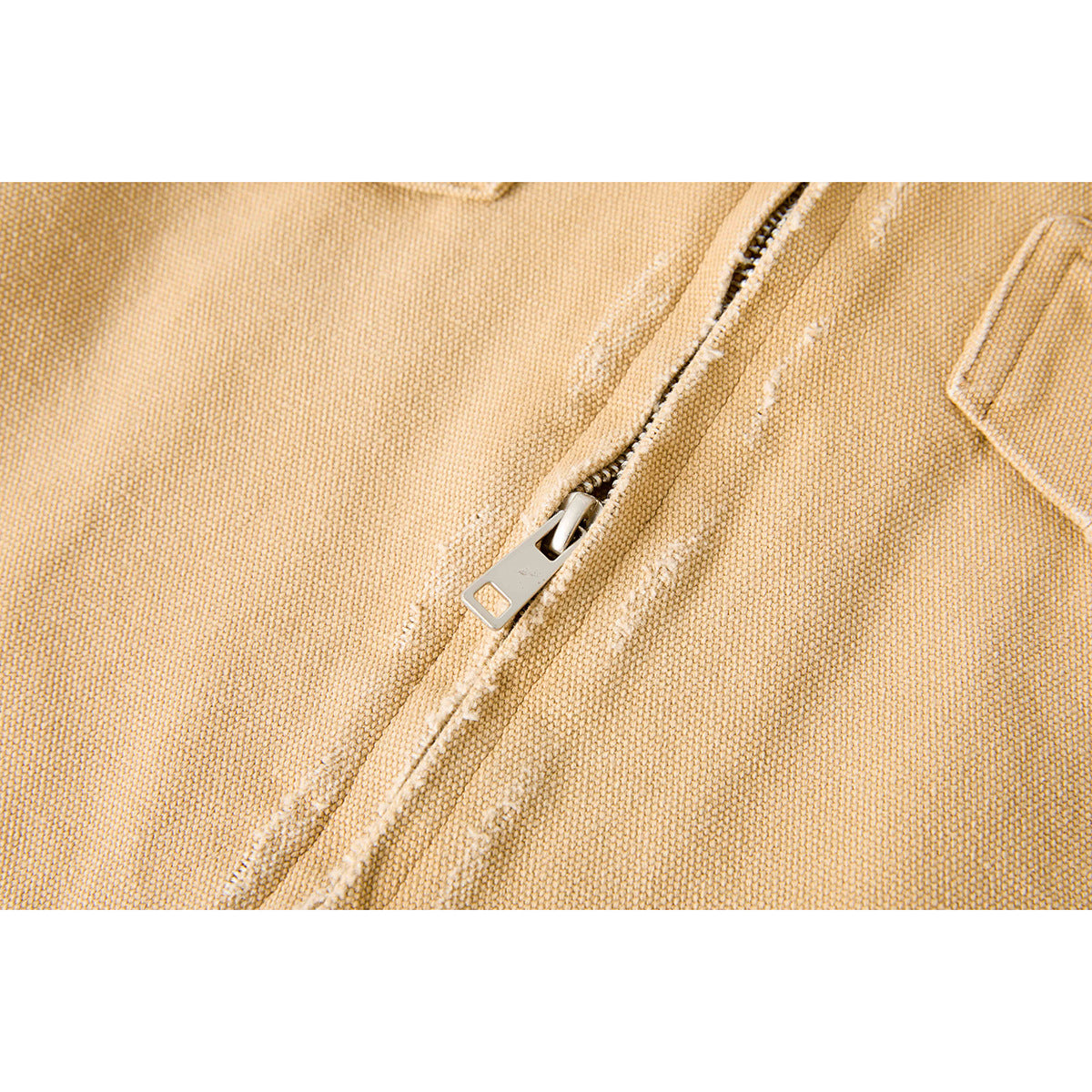 Close-up of the metal zipper and textured tan jacket fabric.