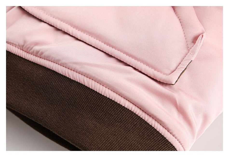Close-up of the jacket’s pink fabric, pocket edge, stitching, and dark brown ribbed hem.