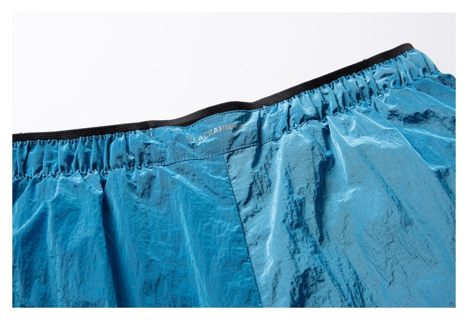Close-up of the elastic waistband on turquoise patterned shorts, with a small BLACKARM mark.