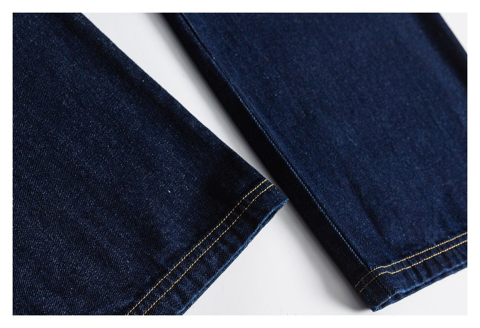 Close-up of two dark indigo denim pant legs with double-stitched hems.