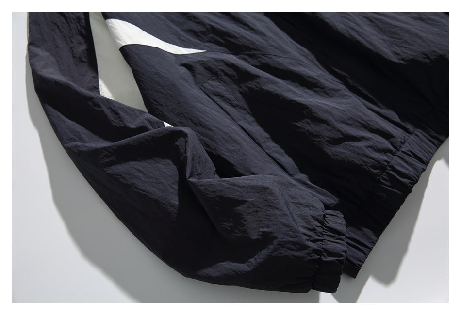 Close-up of a navy windbreaker sleeve, elastic cuff, and side pocket.