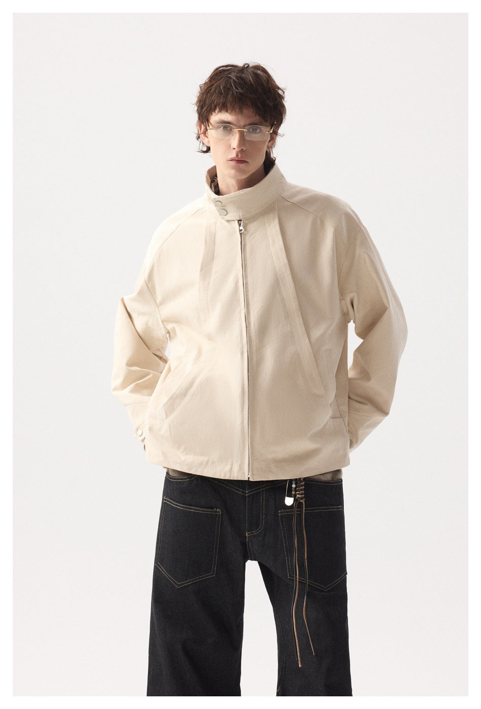 Model wearing a light beige zip-front jacket with a high snap collar and angled pockets, shown from the front.