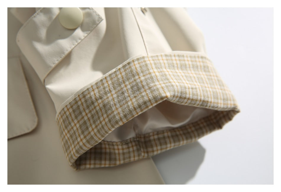 Close-up of the coat's beige-and-white plaid cuff lining and ivory sleeve tab.