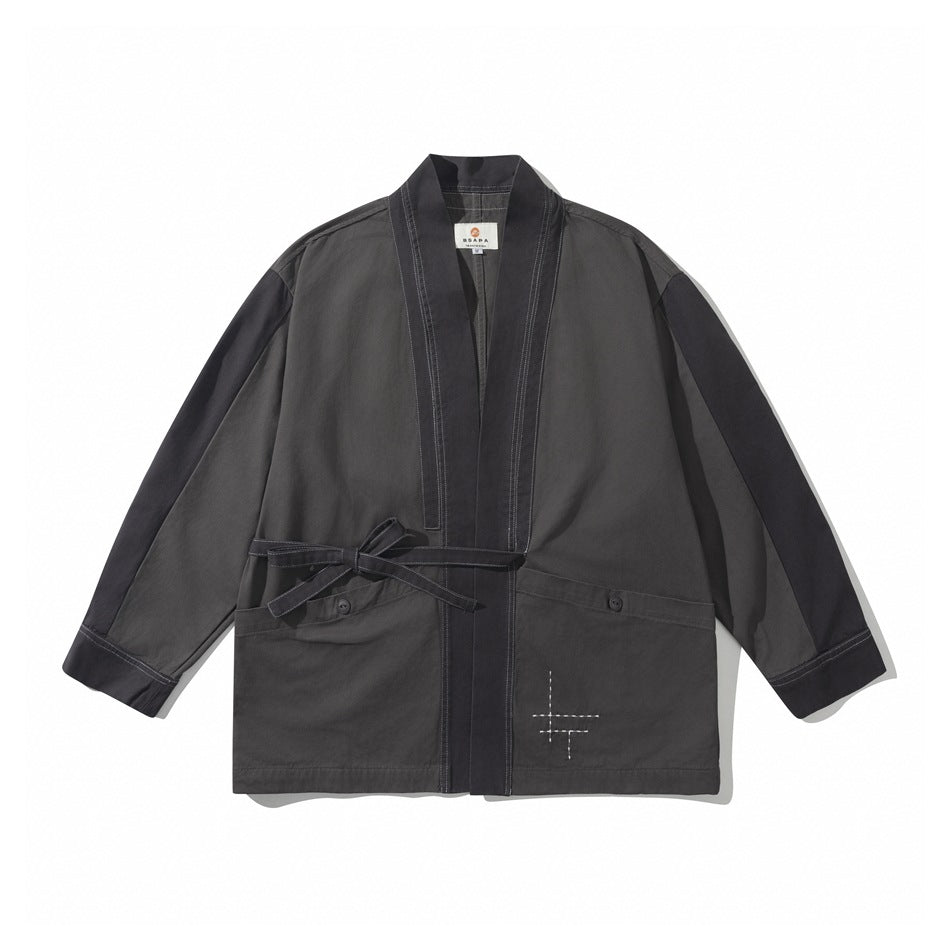 Gray kimono-style jacket with dark contrast trim, side tie belt, button-flap pockets and white stitched cross detail