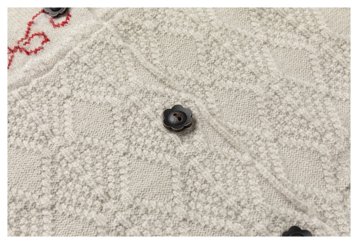 Close-up of textured cream cardigan knitting and a dark flower-shaped button.