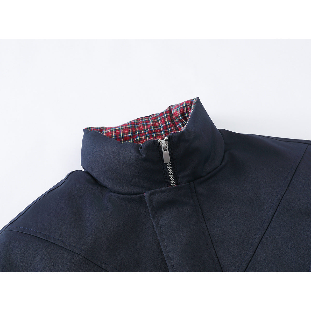 Close-up of a navy jacket’s stand collar, silver zipper, and red plaid lining.