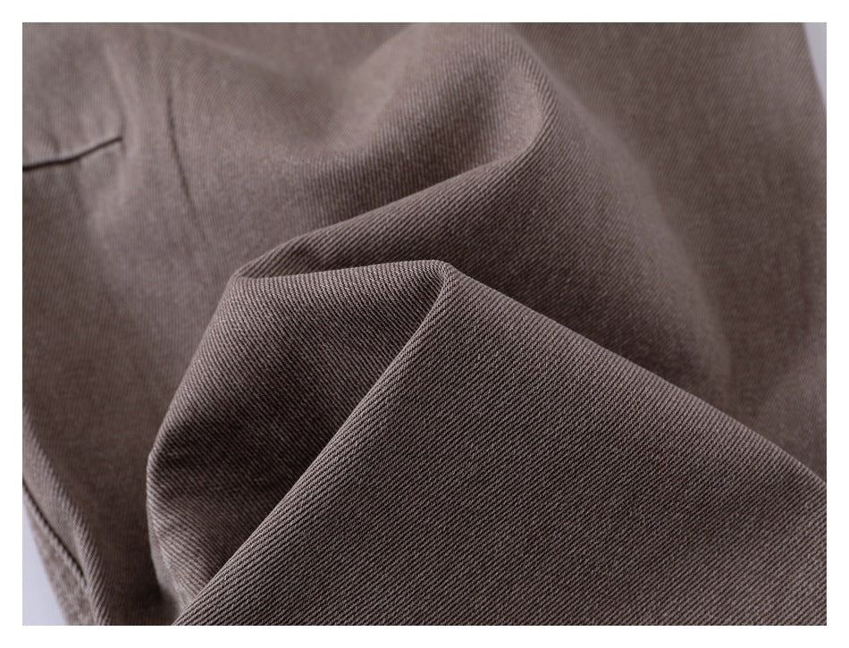 Close-up of taupe-brown fabric folded to show its fine diagonal weave and a stitched seam.