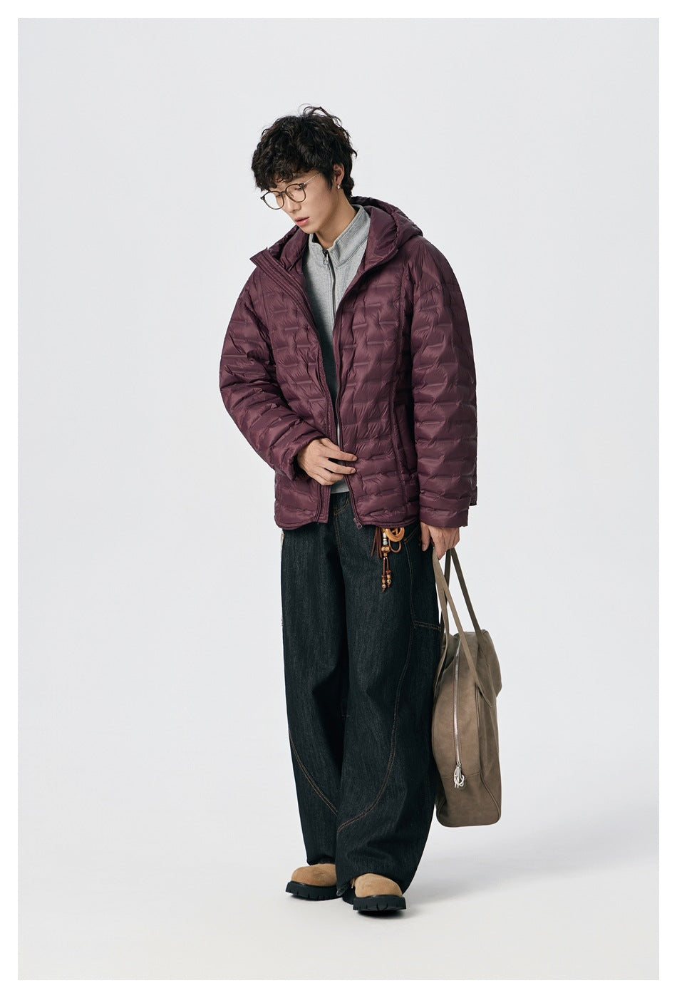 Model wearing a burgundy quilted hooded jacket over a gray top and dark wide-leg jeans.