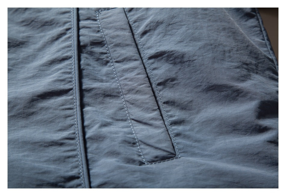 Close-up of a slate-blue jacket's stitched vertical placket and surrounding fabric.