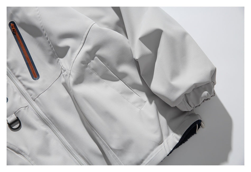Close-up of the light gray jacket's sleeve, elastic cuff, side pocket, and orange-accented chest zipper.