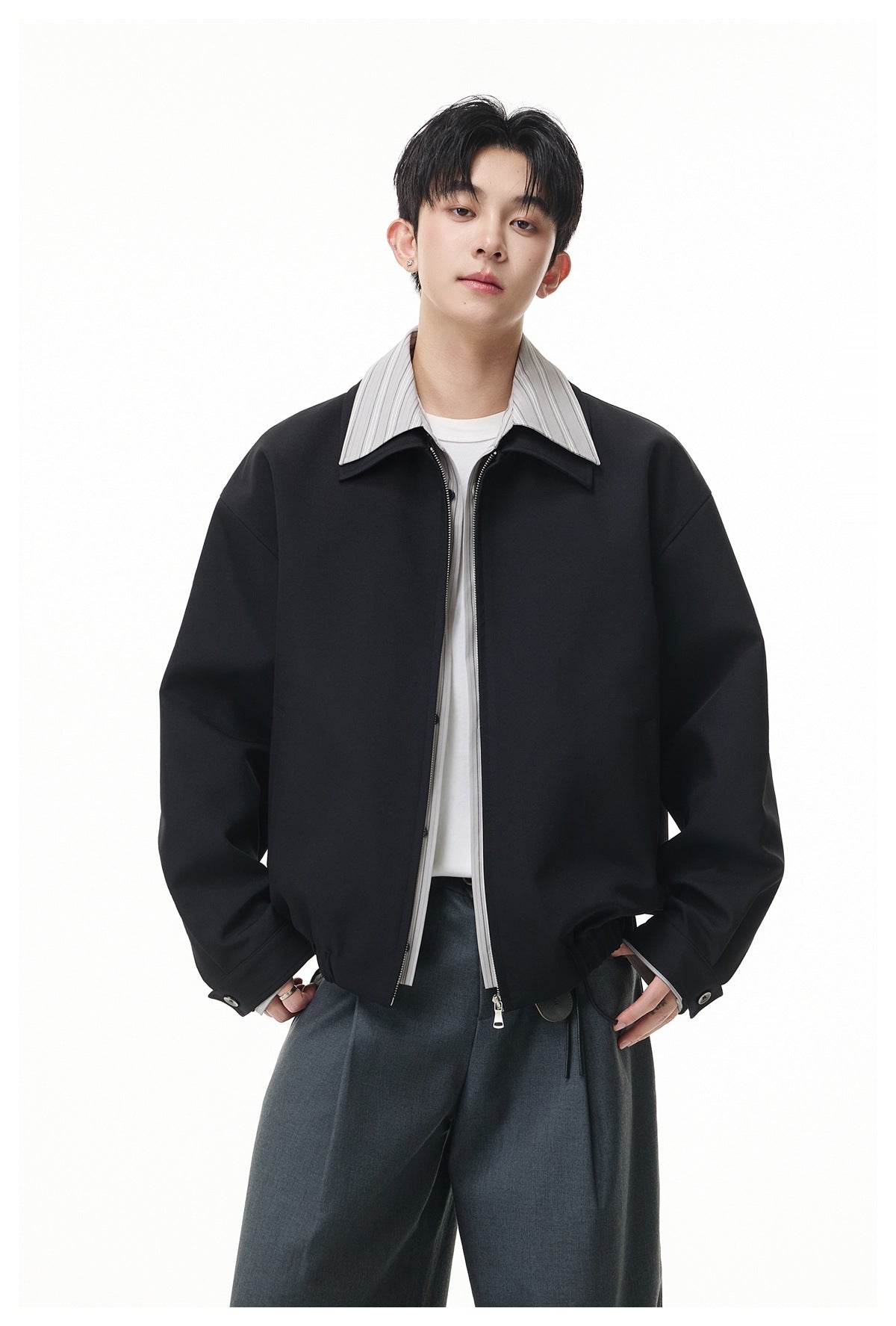 Front view of a model wearing a black oversized zip jacket with a wide collar and elastic hem.