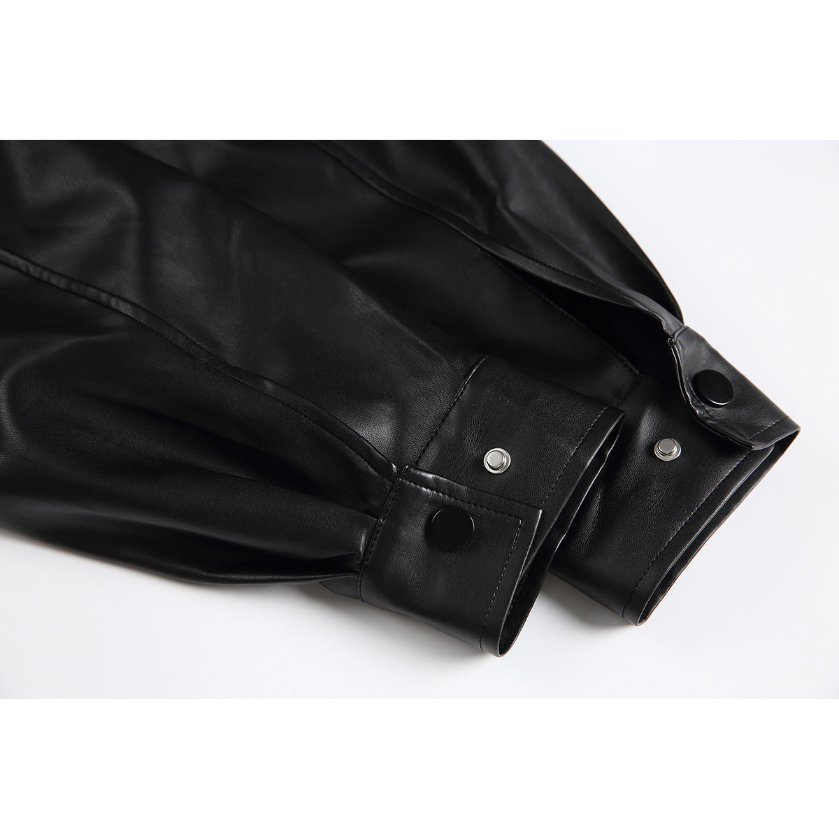 Close-up of black jacket sleeves with adjustable snap-button cuffs and visible stitching.