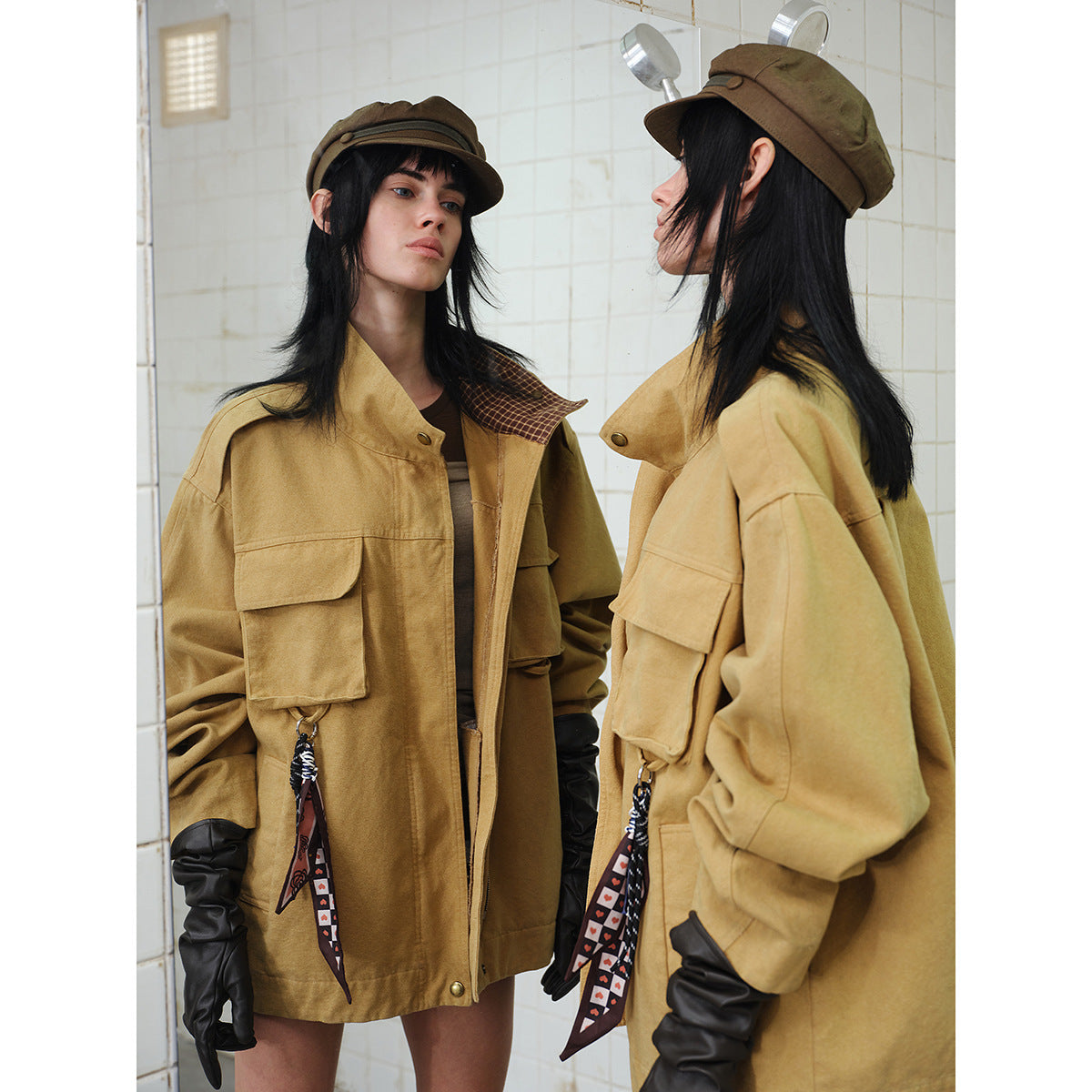 Close view of the tan utility jacket's flap pockets, raised collar, patterned lining, and hanging accessories on a model.