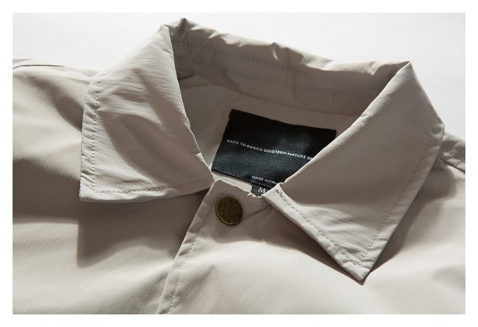 Close-up of the jacket collar, brass-tone button, and sewn-in black neck label.