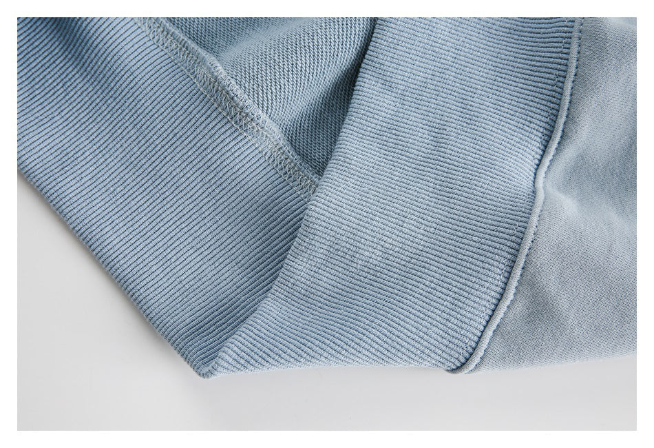 Close-up of pale blue sweatshirt ribbing and visible overlock stitching at a seam.