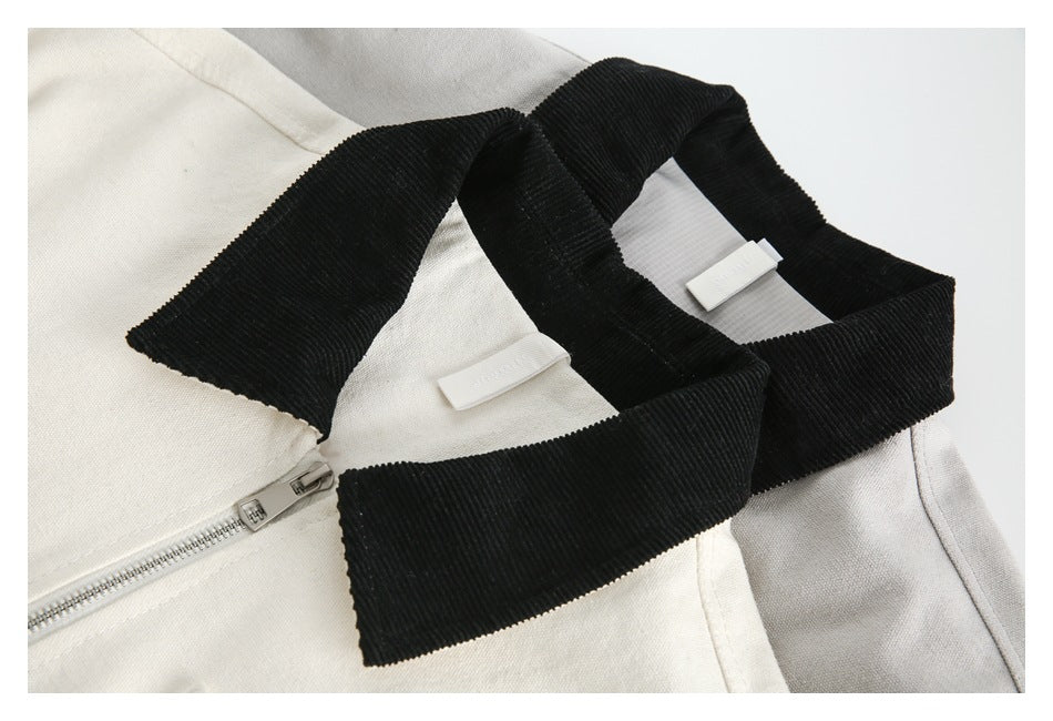 Close-up of a cream zip-front garment with a wide black ribbed collar and zipper.