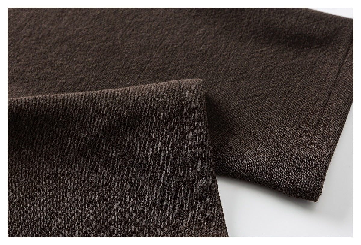 Close-up of dark brown fabric with a folded edge, showing the knit texture and stitching.