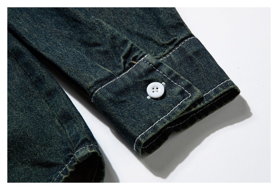Flat-lay close-up of a dark indigo-green sleeve cuff with white stitching and a white button.