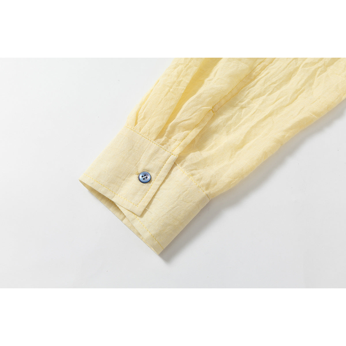 Close-up of a pale yellow shirt sleeve and buttoned cuff.