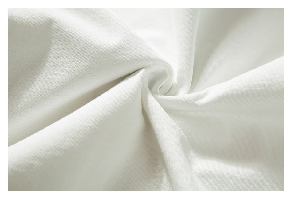 Close-up of white garment fabric gathered into soft folds, showing its surface texture.