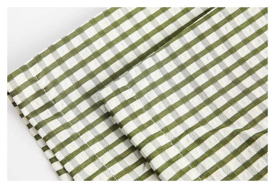 Folded olive green and cream checked fabric showing its striped pattern and stitched edge.