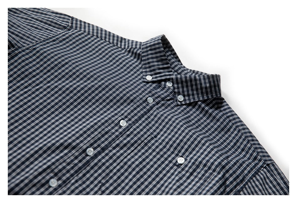Close-up of a navy plaid button-up shirt showing the collar, white buttons and upper front.