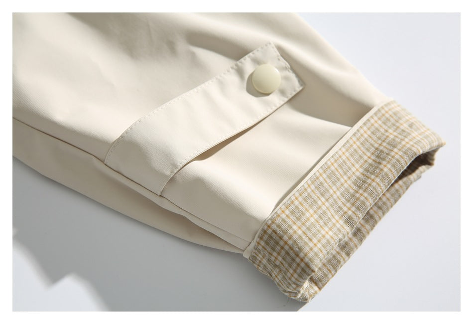 Cream garment cuff with a buttoned tab and beige plaid lining.