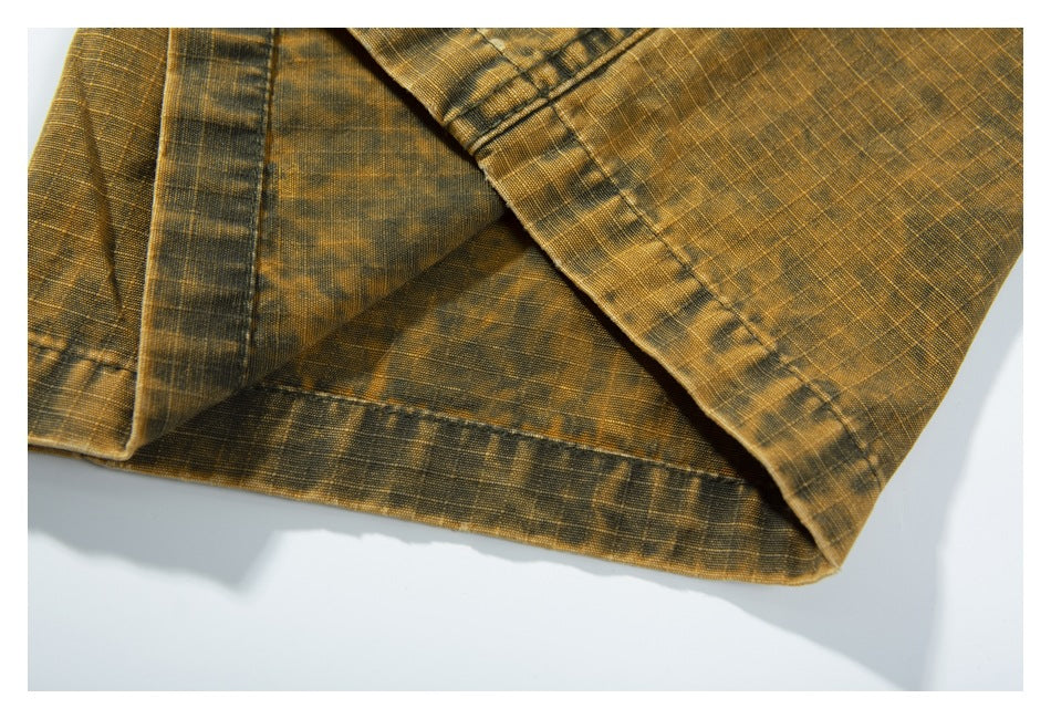 Close-up of a mustard-brown garment hem and stitched seams with a subtle dark plaid pattern.