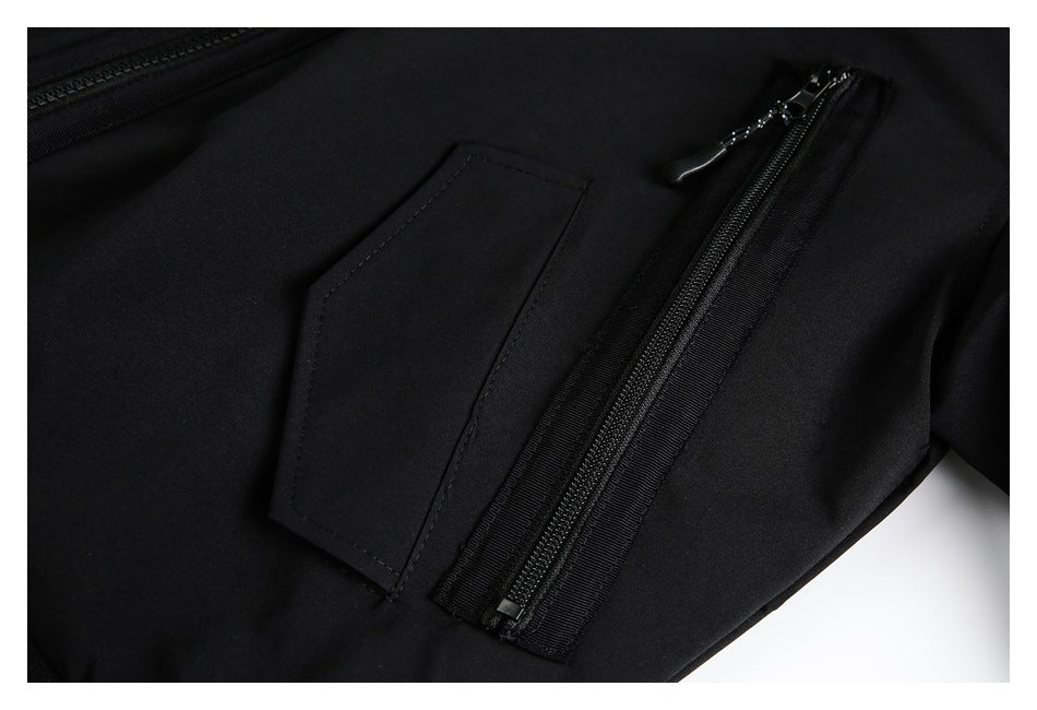 Close-up of a black garment showing a slanted zipper pocket beside a stitched fabric panel.