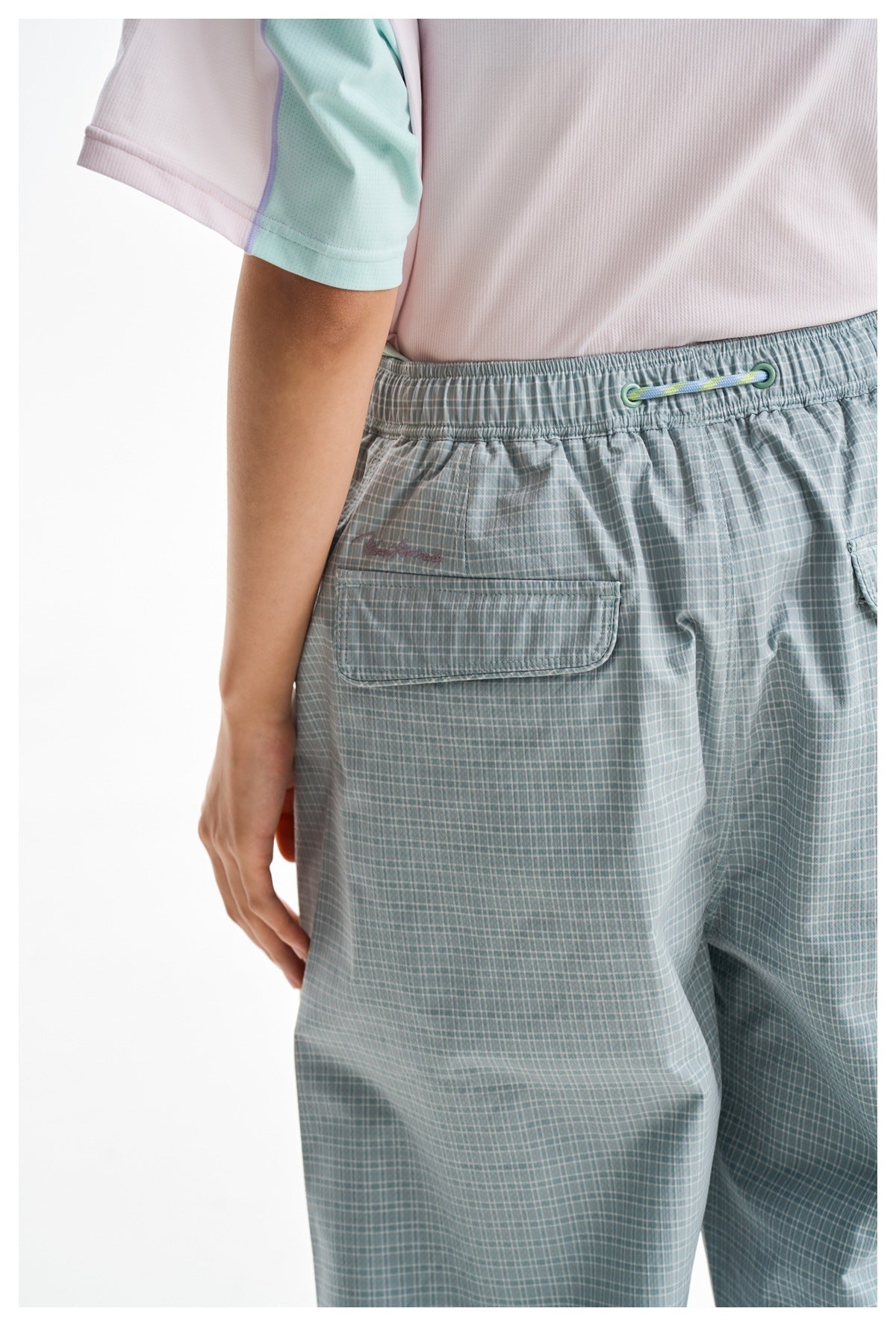 Close-up of the trousers' elastic back waist, drawcord, and rear pocket in a pale blue-gray check pattern.