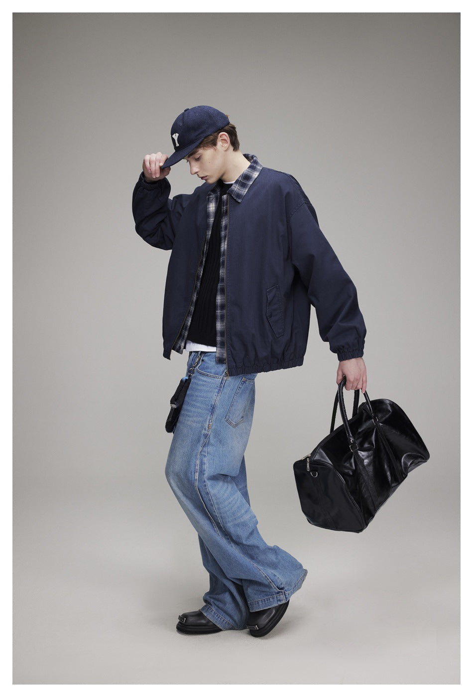 Side pose of a model wearing the navy jacket with plaid trim and elastic hem.