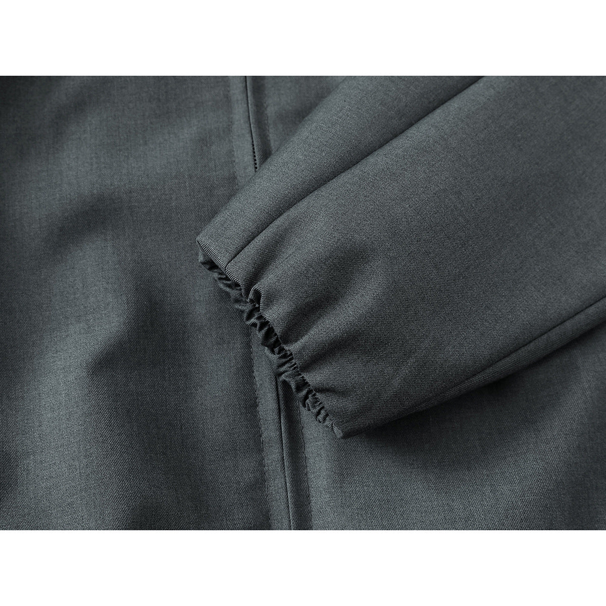 Close-up of a charcoal gray jacket sleeve with a gathered cuff and visible stitching.