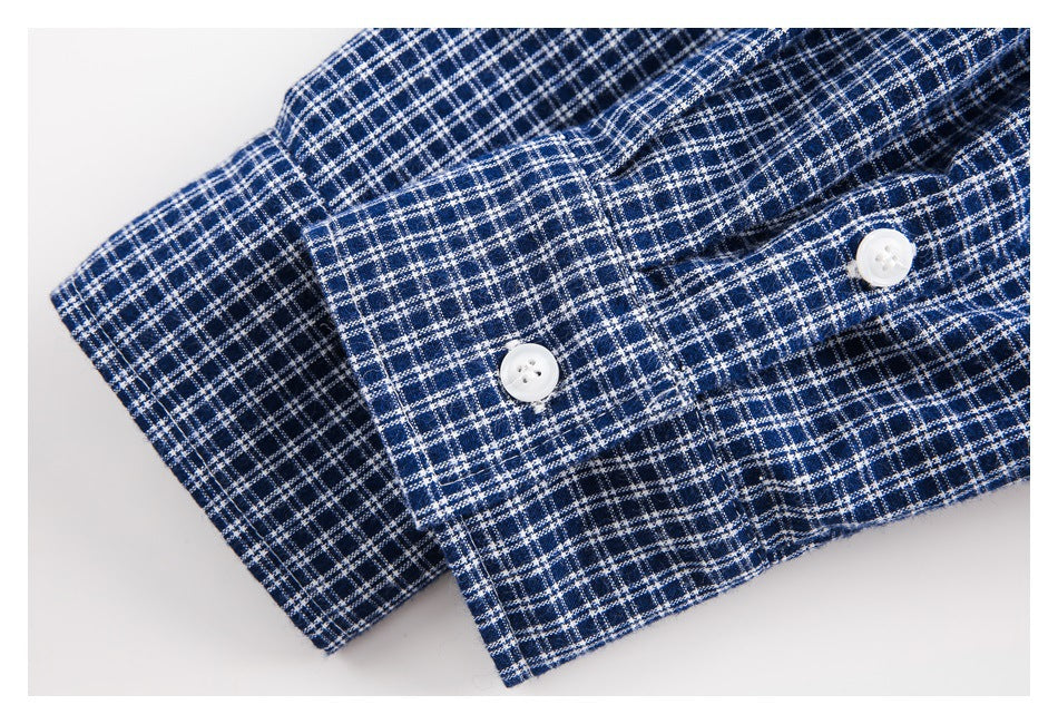 Close-up of a navy and white checked shirt cuff with two white buttons.
