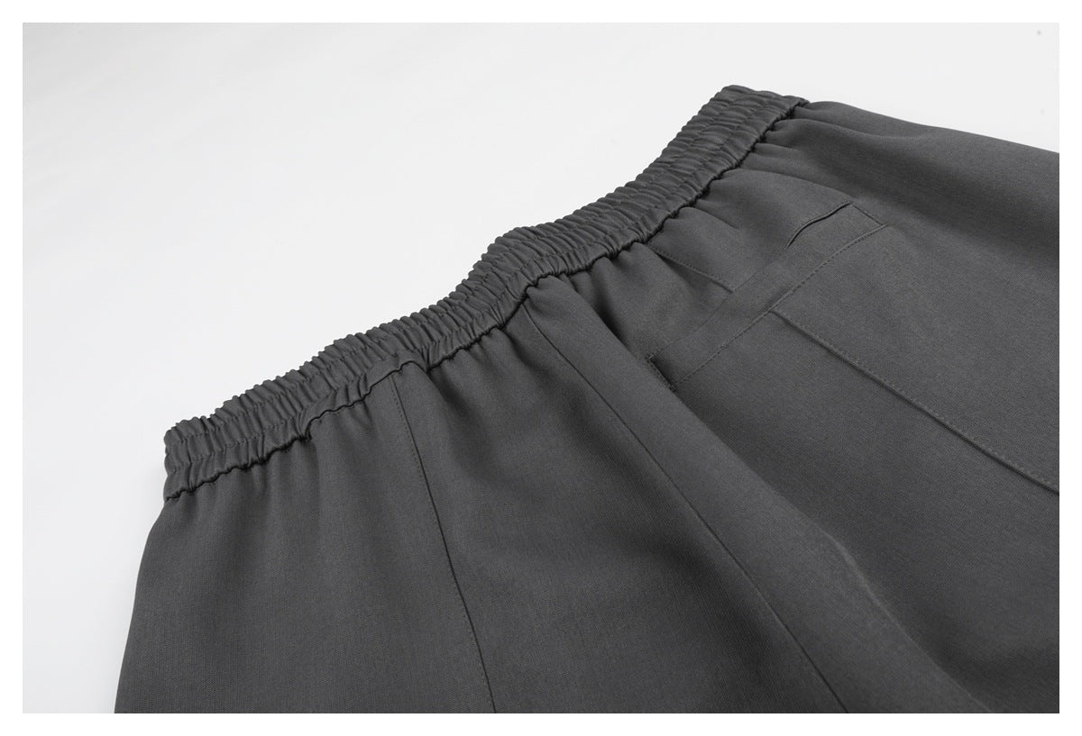 Close-up of charcoal gray pants with a gathered elastic waistband and a back pocket.