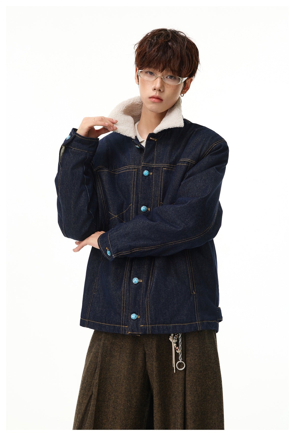 Model wearing a dark indigo denim jacket with a cream sherpa collar, contrast stitching, and turquoise buttons.