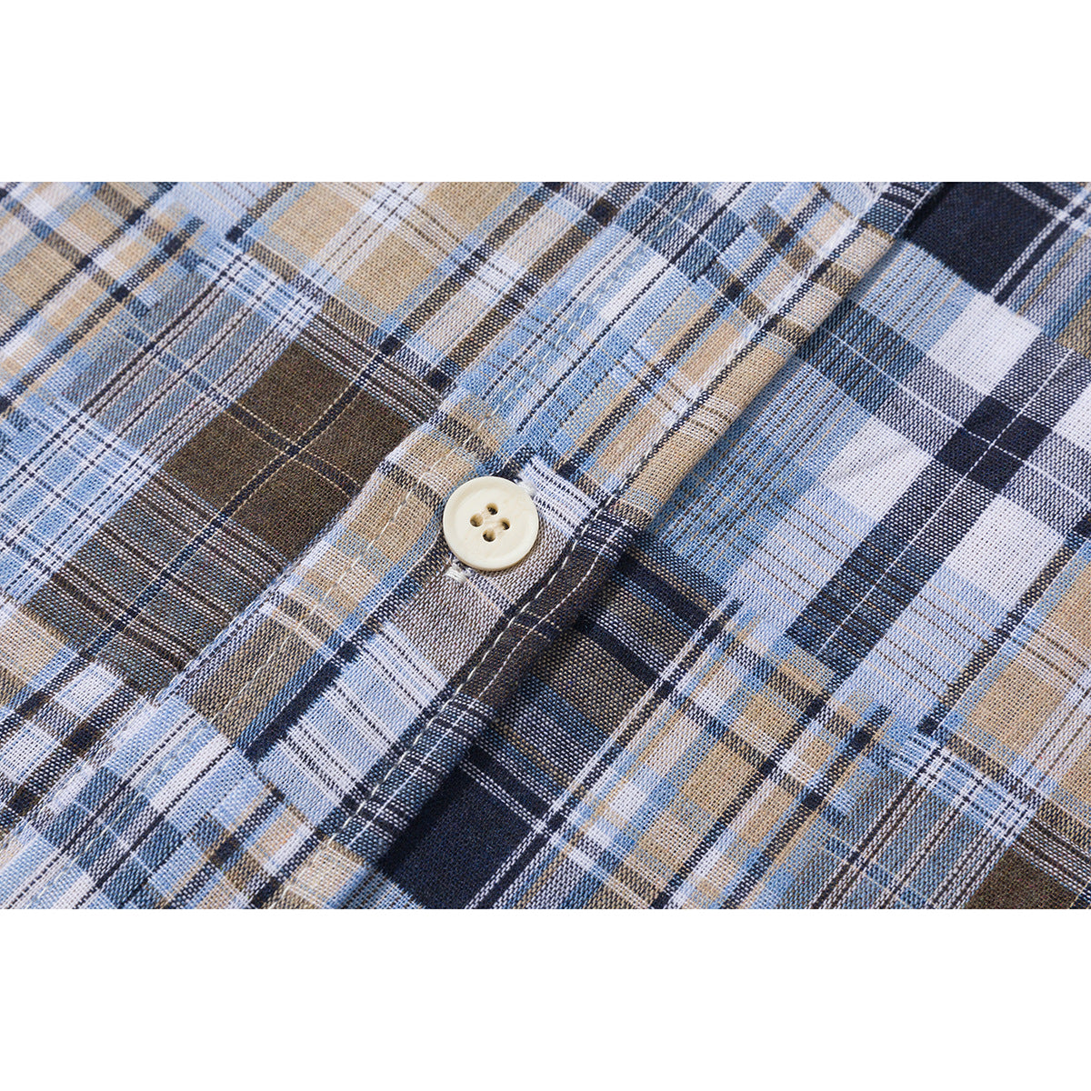 Close-up of a cream button on blue, brown, navy, and white plaid shirt fabric.