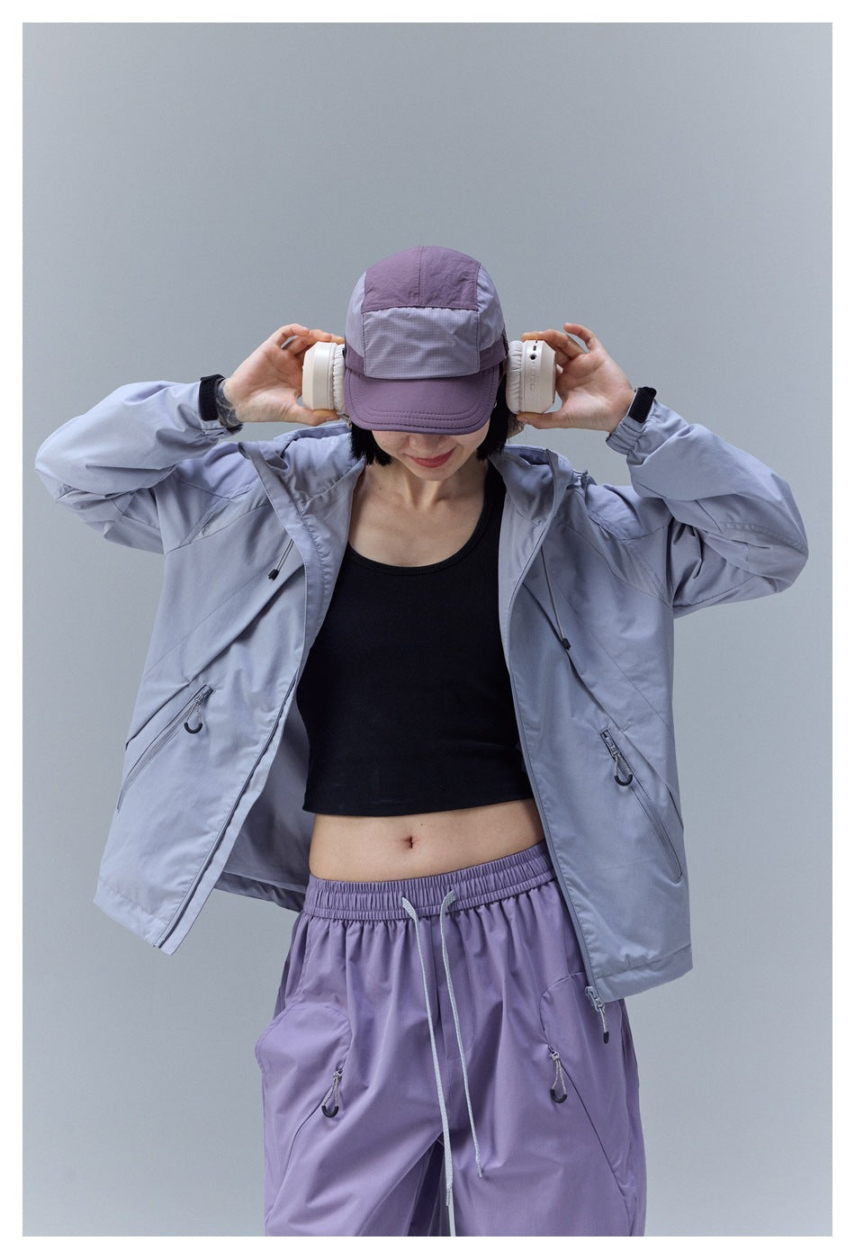 Closer view of a model wearing an open light gray hooded jacket and lavender drawstring pants.