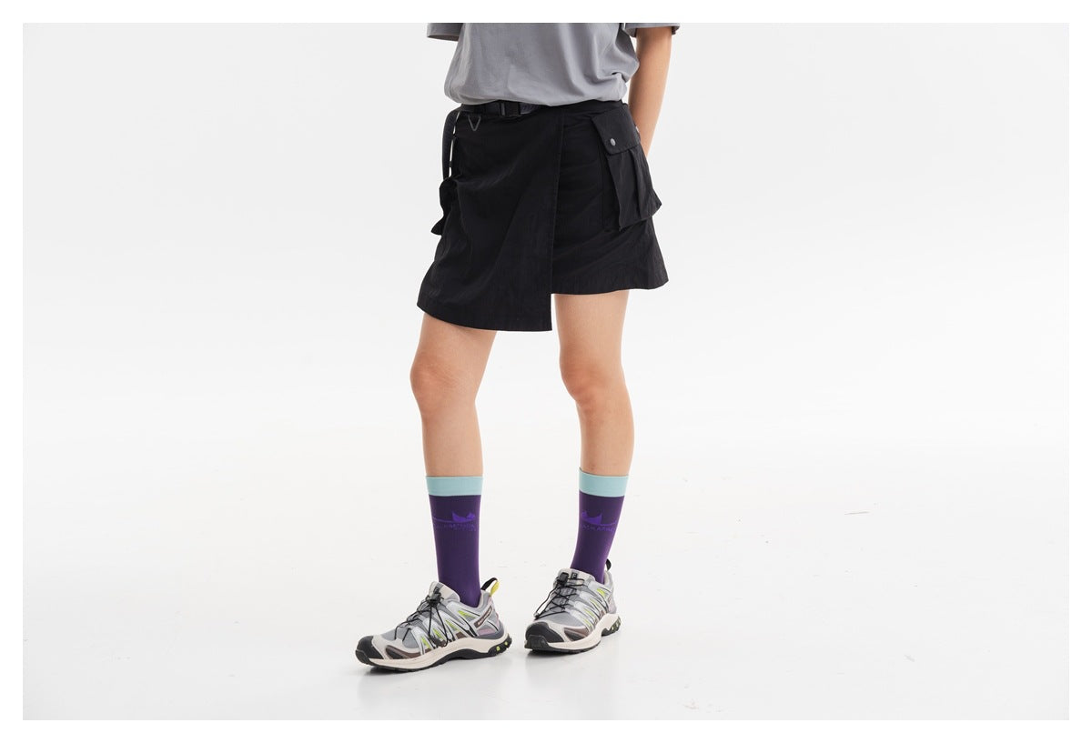 Cropped view of a model wearing a black wrap-style cargo skirt with a belt and flap pockets.