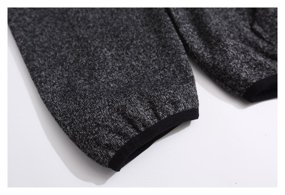 Close-up of a sleeve cuff with black edging on dark heather-gray fabric.