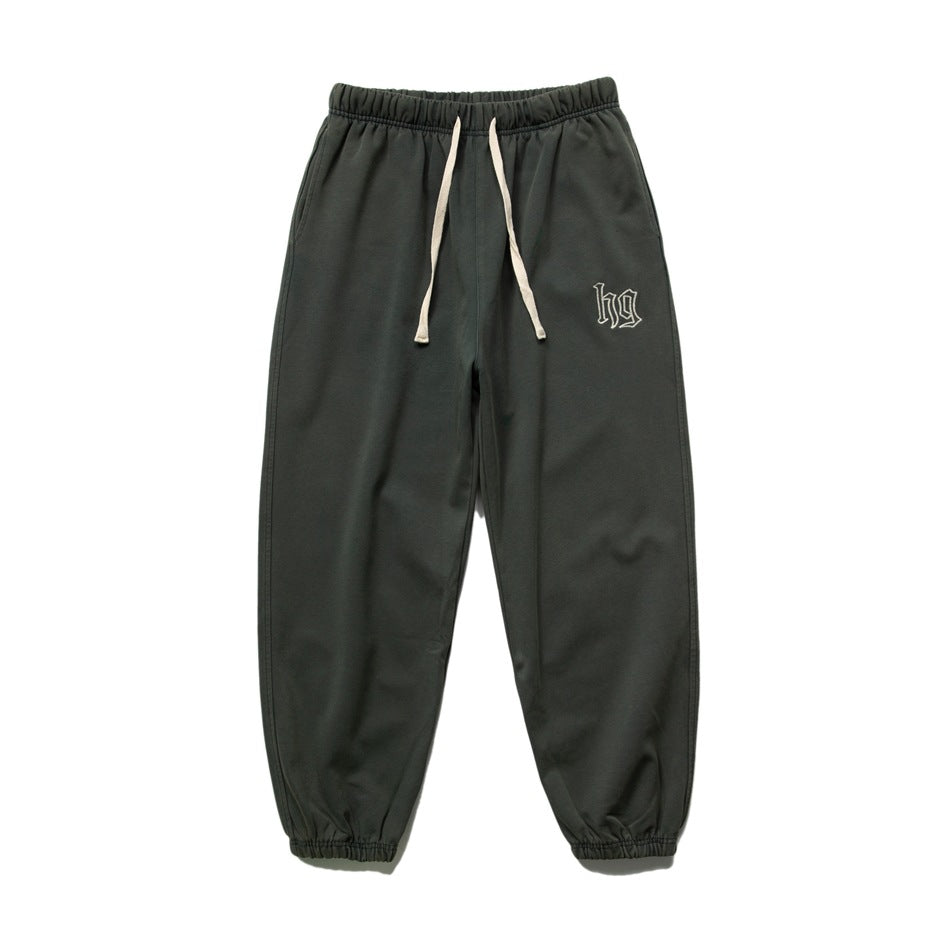 Dark green sweatpants flat lay with cream drawstring, elastic cuffs and embroidered hg logo