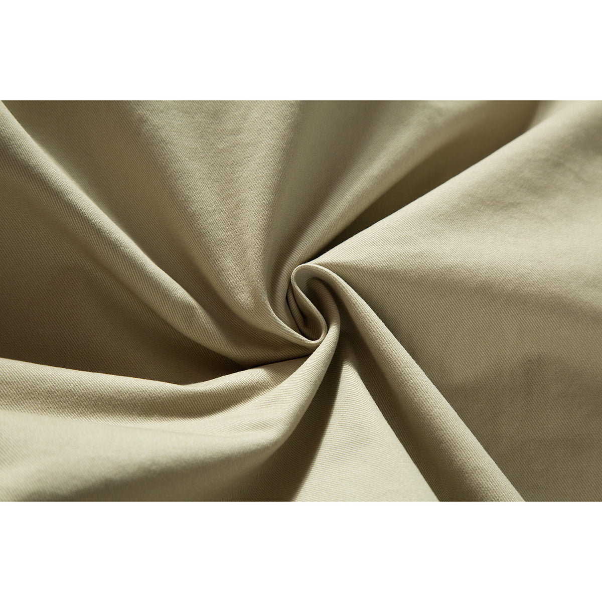 Close-up of light khaki fabric gathered into folds, showing its fine diagonal surface texture.