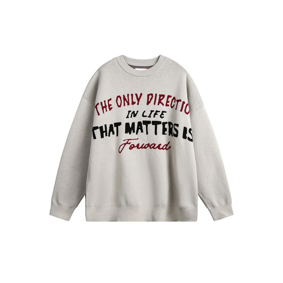 Light beige-gray crewneck sweater with red and black knitted slogan across the chest, flat lay on white