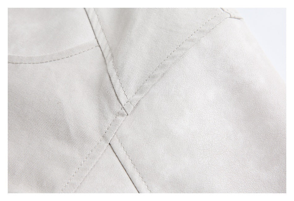Close-up of a pale gray-beige garment showing intersecting stitched seams and textured panels.
