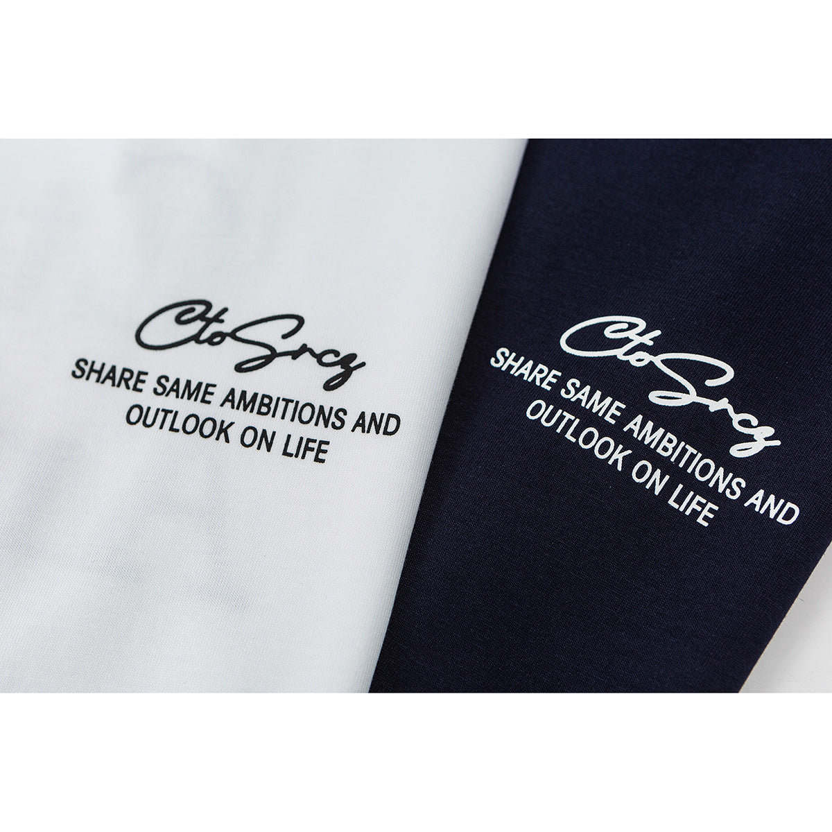 Close-up of black slogan prints on white and navy T-shirt fabric.