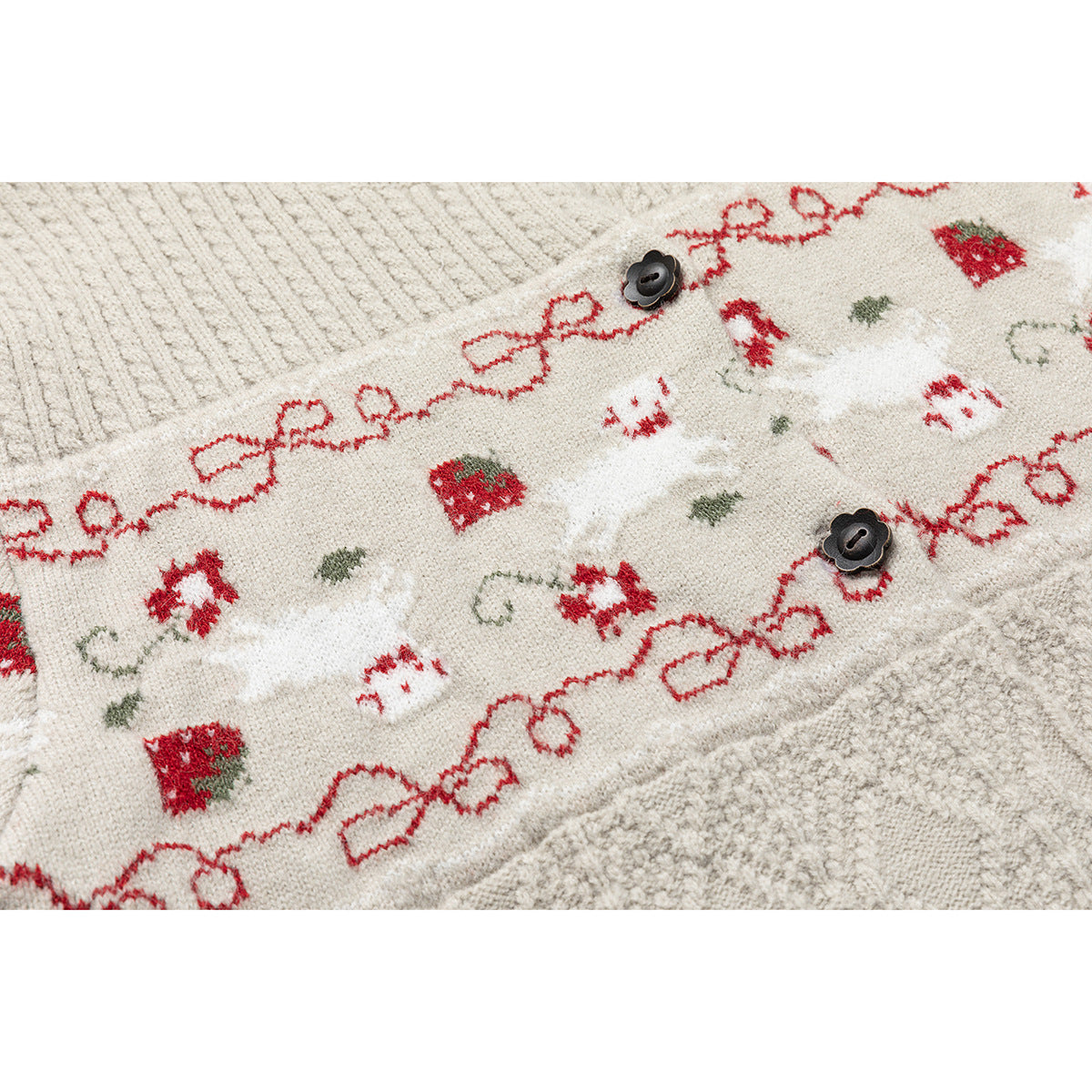 Close-up of a cream cardigan with dark buttons and a red bow-and-strawberry patterned band.