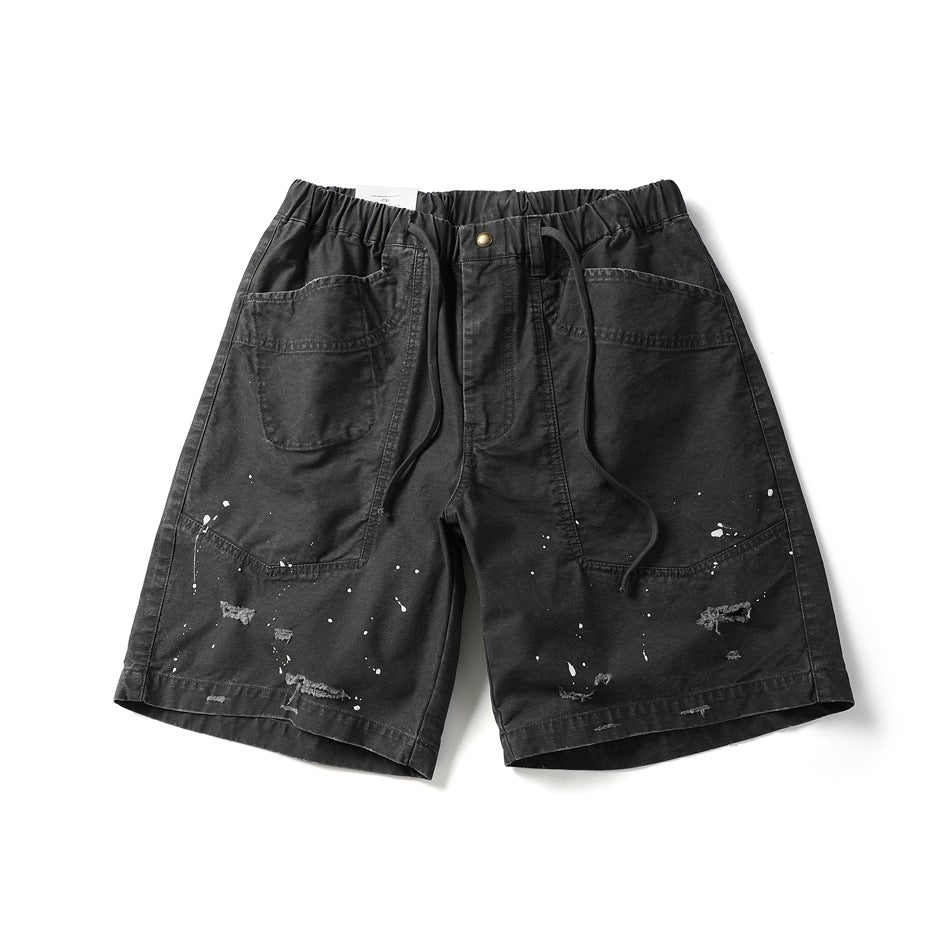Dark gray knee-length shorts with elastic drawstring waist, large front patch pockets, paint splatters and frayed rips