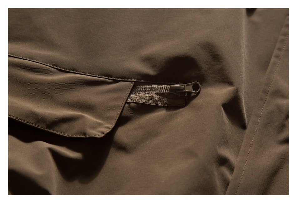 Close-up of a dark brown jacket's flap pocket and short horizontal zipper.