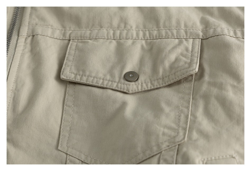 Close-up of a beige garment snap-flap pocket with visible stitching and a zipper at the side.