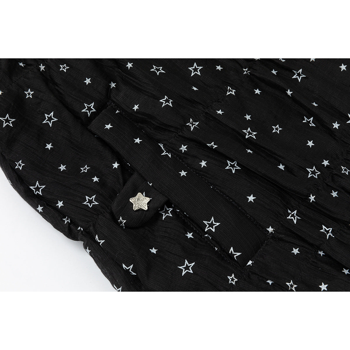 Close-up of the black jacket's white star print and a small metal star button on a fabric tab.