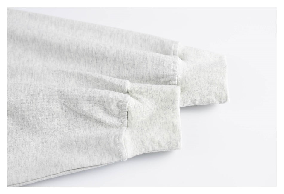 Close-up of two light gray heather sleeves ending in wide ribbed cuffs.